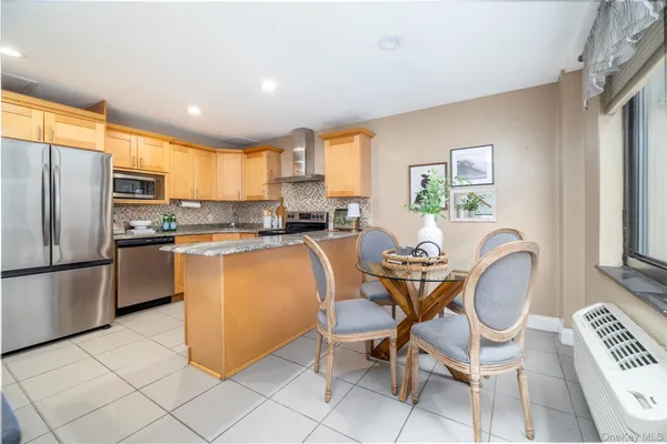 a kitchen with granite countertop cabinets a dining table and a refrigerator