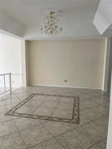 a view of an empty room with window and chandelier fan