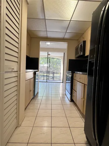 a hallway with white cabinets and black appliances