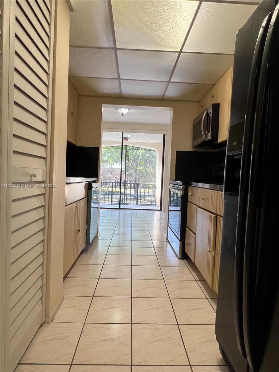 3760 Inverrary Drive, Unit 2Z Lauderhill, FL 33319 - Photo 8 of 34 a hallway with white cabinets and black appliances