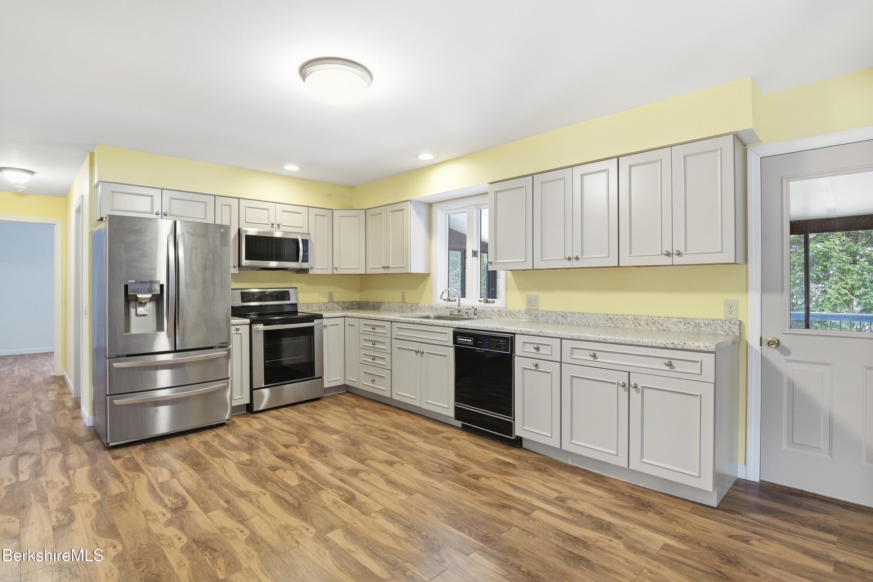 11 Opeechee Street Lanesborough, MA 01237 - Photo 14 of 35 a kitchen with granite countertop a refrigerator oven a sink dishwasher and white cabinets with wooden floor