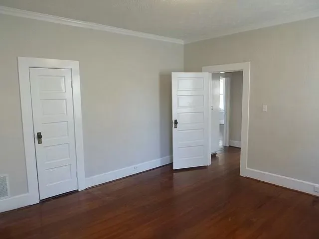 an empty room with wooden floor & closet area