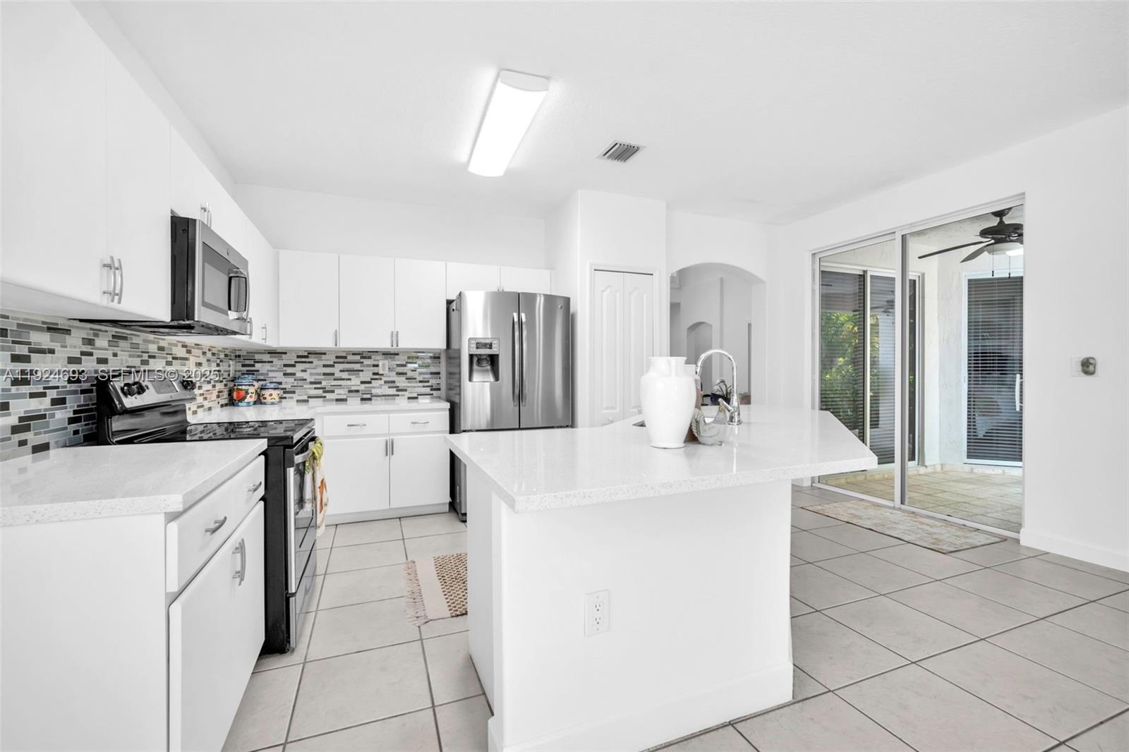 13030 Northwest 8th Street Miami, FL 33182 - Photo 29 of 54 a kitchen with stainless steel appliances a white stove top oven and white cabinets next to a window