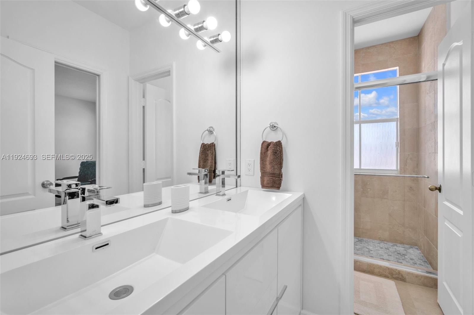 13030 Northwest 8th Street Miami, FL 33182 - Photo 38 of 54 a bathroom with double vanity sinks and a mirror