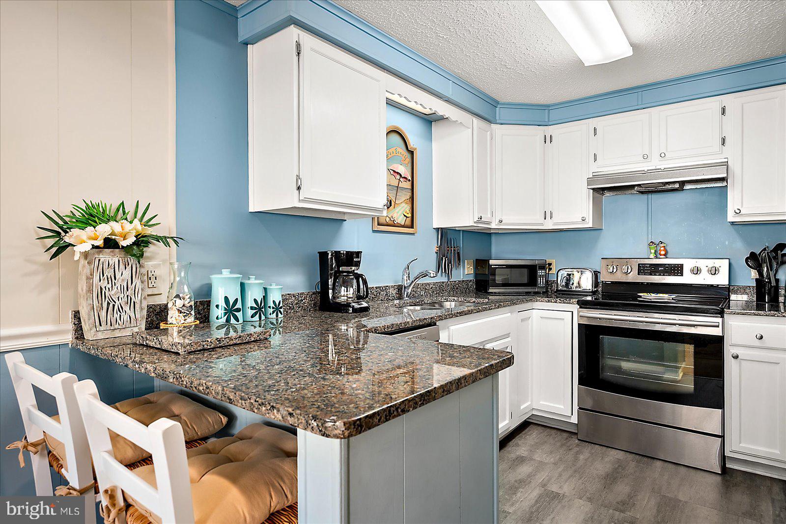 a kitchen with stainless steel appliances granite countertop a stove a sink and a white cabinets