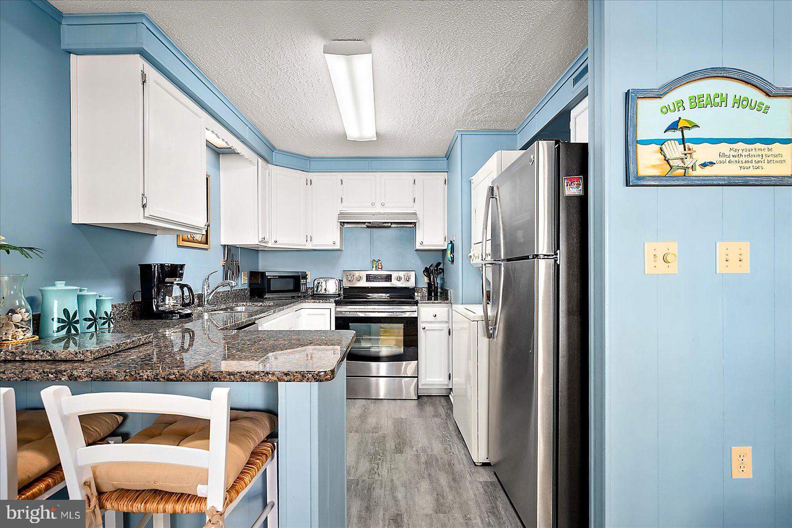9 46th Street, Unit 22 Ocean City, MD 21842 - Photo 11 of 43 a kitchen with stainless steel appliances granite countertop a refrigerator a stove a sink dishwasher and white cabinets with wooden floor