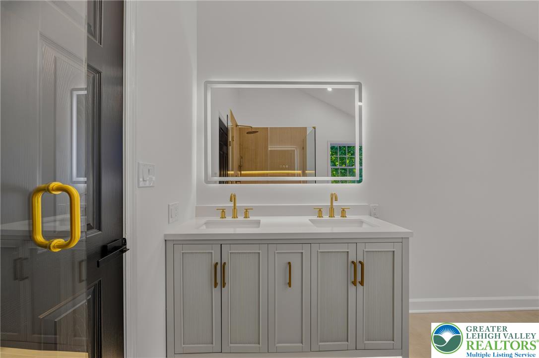 3130 Muirfield Road Center Valley, PA 18034 - Photo 35 of 63 A contemporary double vanity pairs sleek cabinetry with integrated mirror lighting in this bathroom.