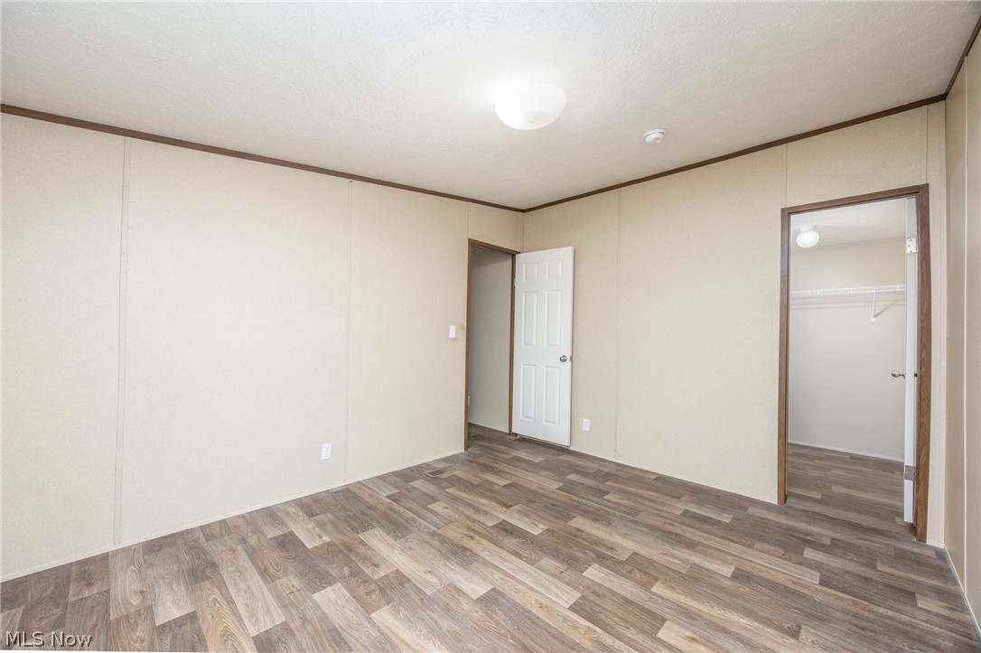 7455 Stanleyville Road Whipple, OH 45788 - Photo 24 of 37 Spacious room featuring wood-finish flooring, light beige panel walls with dark trim, and an overhead flush-mount light fixture