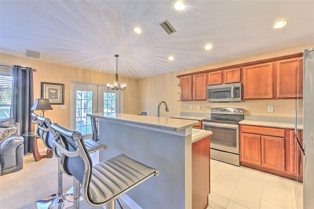 7352 Bridgeview Drive Zephyrhills, FL 33545 - Photo 17 of 49 a kitchen with stainless steel appliances granite countertop a stove top oven a sink dishwasher a dining table and chairs with wooden cabinets