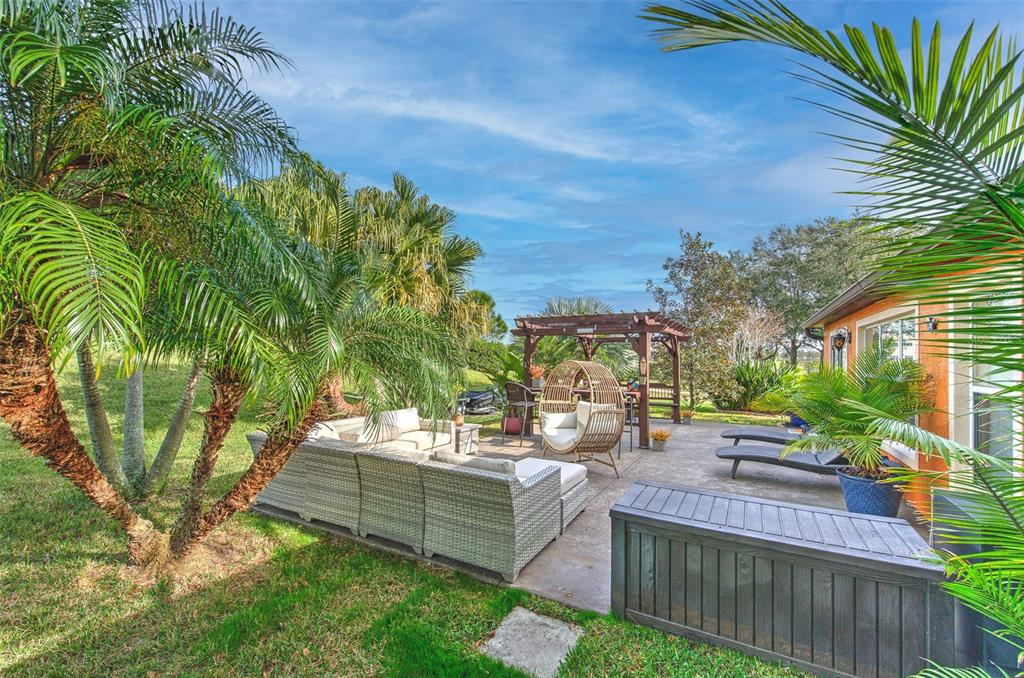 7352 Bridgeview Drive Zephyrhills, FL 33545 - Photo 34 of 49 a view of a patio with couches and table and chairs with wooden fence and plants