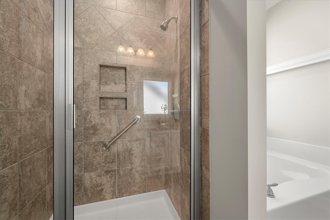 21 Barron Glenn Way Anderson, SC 29621 - Photo 32 of 48 This Primary Bathroom features a tiled walk-in shower with glass enclosure and a grab bar, alongside a pristine bathtub.