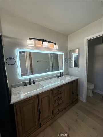 a bathroom with a double vanity sink and mirror with toilet