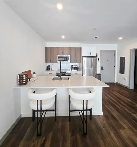 a kitchen with stainless steel appliances a dining table chairs and wooden floor