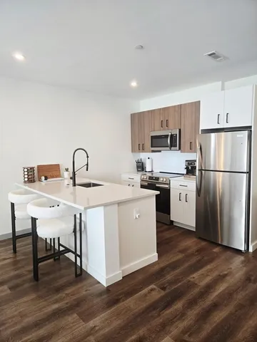 a kitchen with a refrigerator a sink cabinets and wooden floor