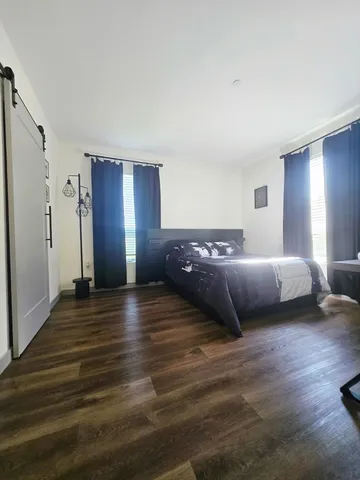 a spacious bedroom with a bed and wooden floor