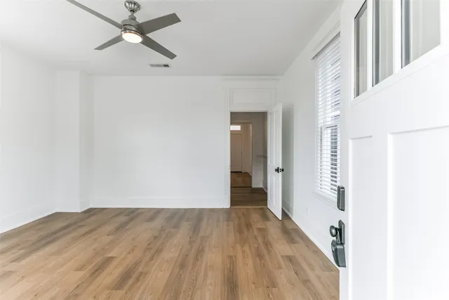 an empty room with wooden floor closet and windows