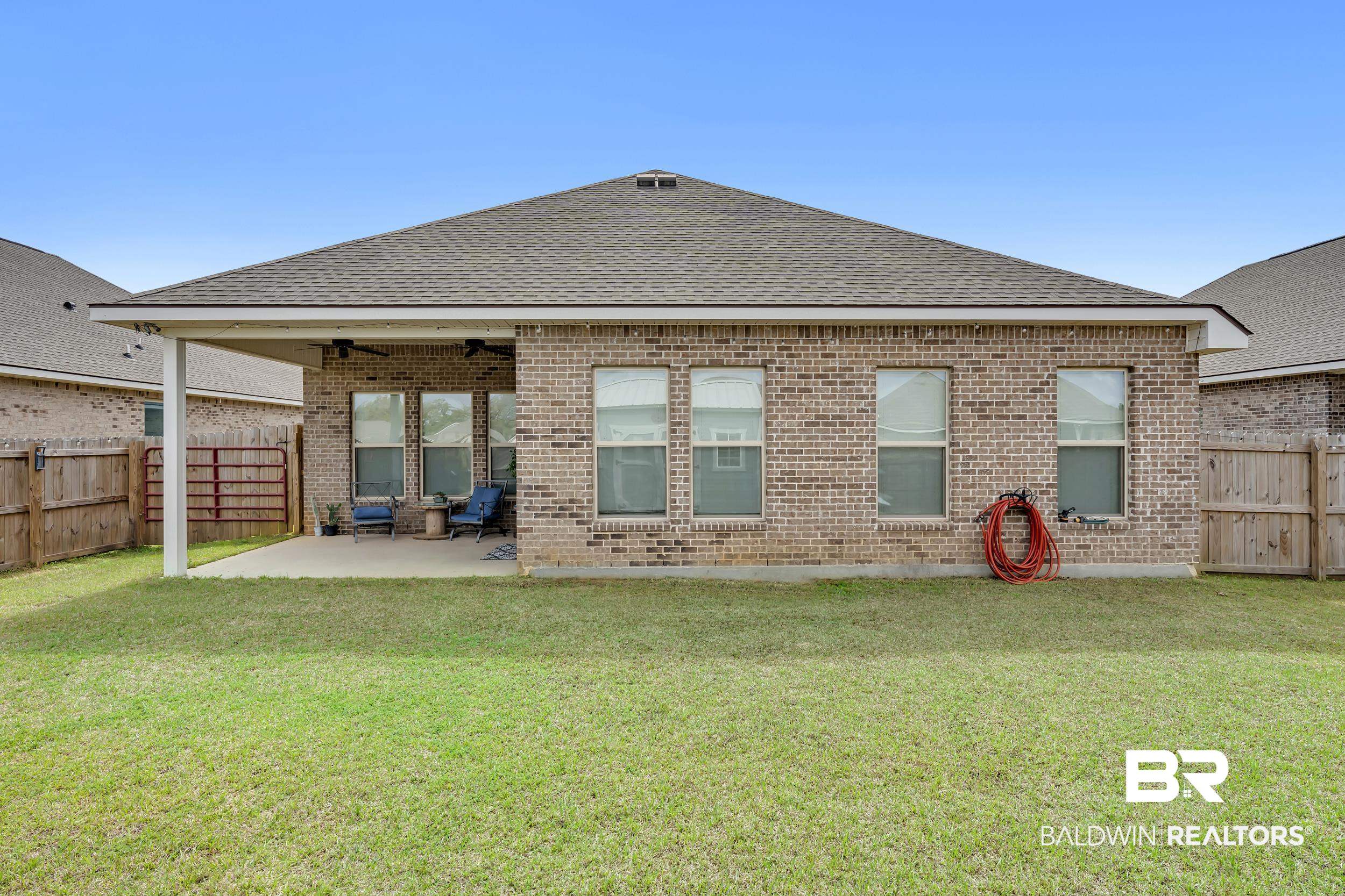 1176 Stella Road Foley, AL 36535 - Photo 33 of 40 Back of house with a fenced backyard, roof with shingles, a patio area, and brick siding