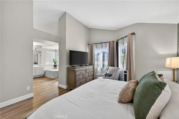 a bedroom with a large bed and a flat tv screen on a dresser