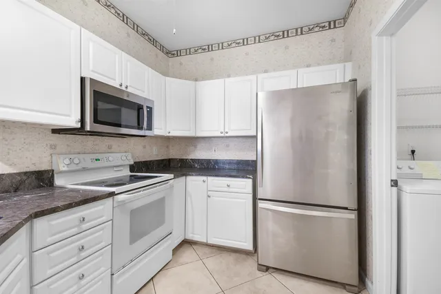 a kitchen with granite countertop white cabinets white stainless steel appliances and a sink