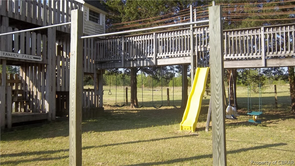 705 Greys Point Road Topping, VA 23169 - Photo 20 of 46 View of jungle gym with a deck and a lawn