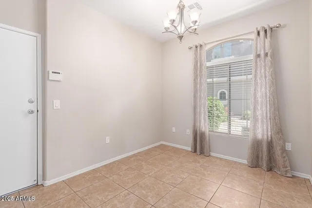 a view of an empty room with window and chandelier fan