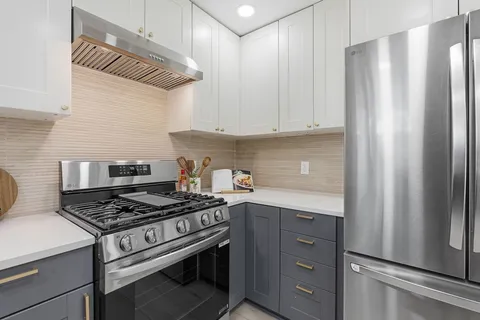 a large kitchen with stainless steel appliances granite countertop a refrigerator and a stove top oven