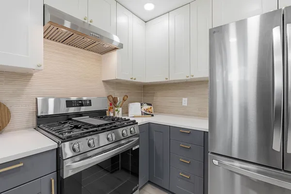 a large kitchen with stainless steel appliances granite countertop a refrigerator and a stove top oven