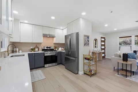 a kitchen with granite countertop a refrigerator stove and sink