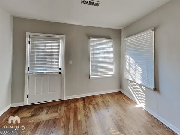 a view of an empty room with a window and wooden floor