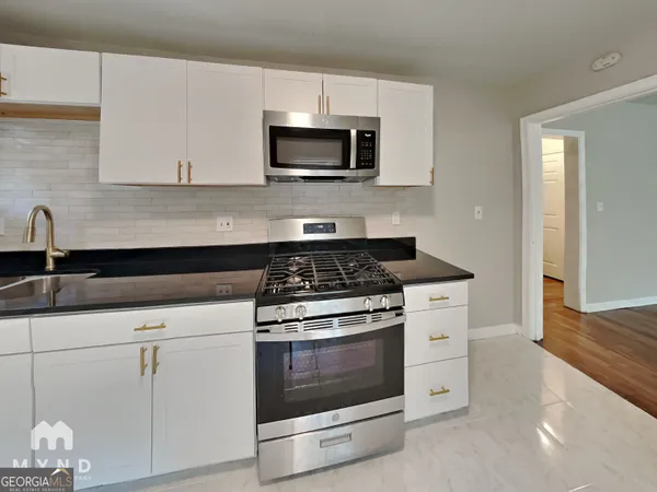 a kitchen with granite countertop white cabinets and appliances
