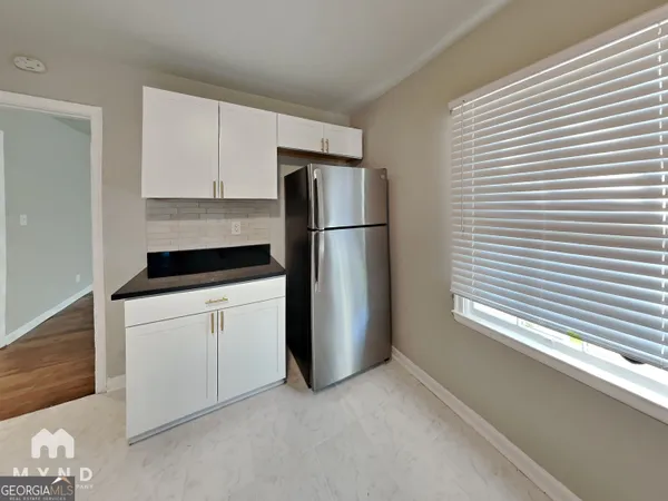 a kitchen with a refrigerator and white cabinets