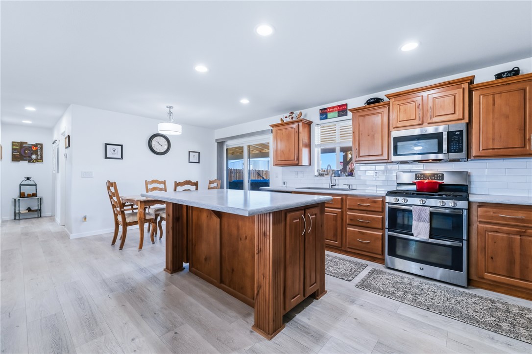 429 South Lochiel Road Golden Valley, AZ 86413 - Photo 16 of 61 Kitchen featuring stainless steel appliances, brown cabinets, recessed lighting, a kitchen island, and light wood-style floors