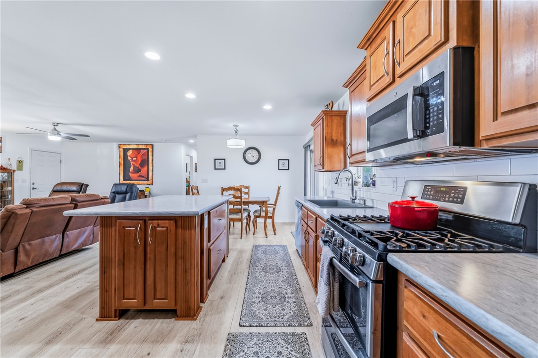 429 South Lochiel Road Golden Valley, AZ 86413 - Photo 61 of 61 Kitchen featuring appliances with stainless steel finishes, brown cabinetry, a center island, light wood finished floors, and open floor plan