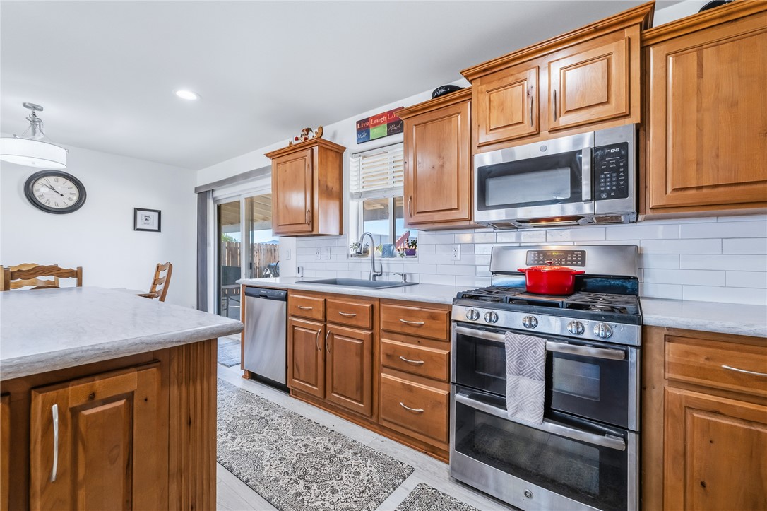 429 South Lochiel Road Golden Valley, AZ 86413 - Photo 19 of 61 Kitchen featuring stainless steel appliances, brown cabinetry, tasteful backsplash, recessed lighting, and light stone countertops