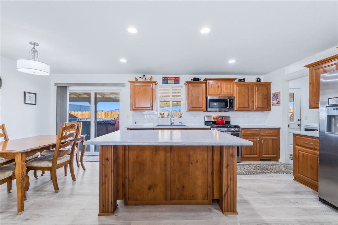 429 South Lochiel Road Golden Valley, AZ 86413 - Photo 20 of 61 Kitchen featuring brown cabinetry, a kitchen island, recessed lighting, tasteful backsplash, and stainless steel appliances