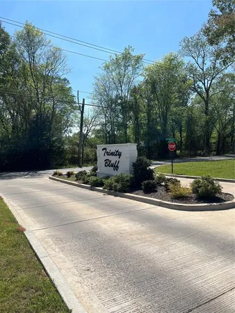 a sign board with flower plants and large trees
