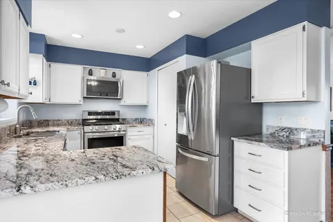 a kitchen with granite countertop a refrigerator stove and microwave