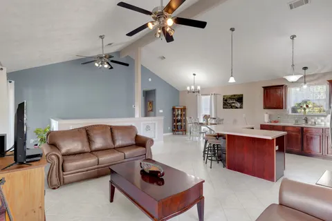 a living room with furniture a ceiling fan and a flat screen tv