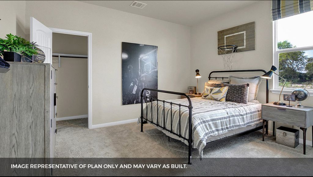 156 Docile Loop San Marcos, TX 78666 - Photo 24 of 40 A well-lit bedroom provides ample space for rest and relaxation, featuring soft carpeting and a window offering natural light.