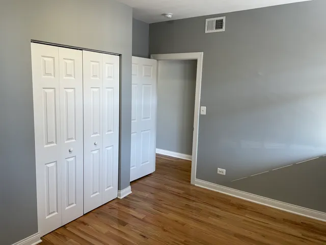 an empty room with wooden floor and closet area