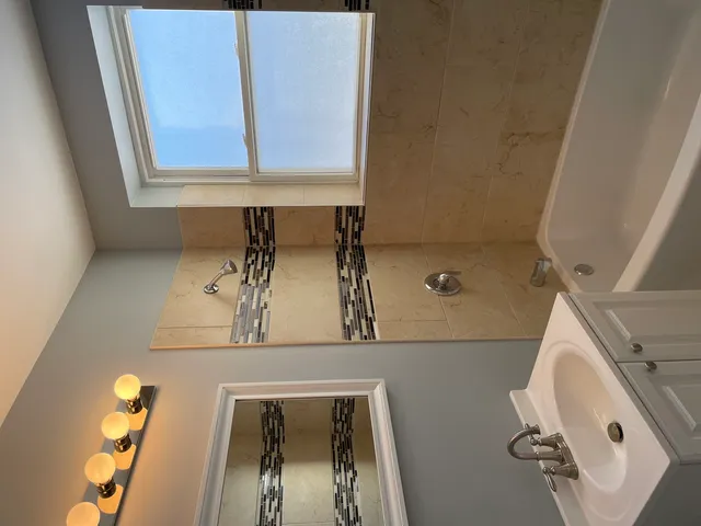 a bathroom with a granite countertop sink a mirror and shower