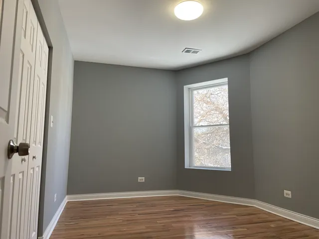 a view of a hallway with wooden floor and a bathroom