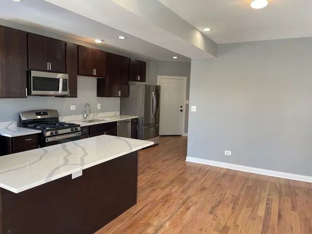 a large kitchen with stainless steel appliances a refrigerator a sink a stove a microwave and cabinets