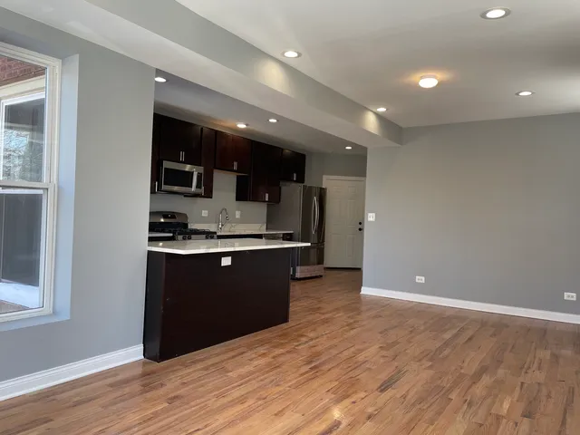 a kitchen with stainless steel appliances kitchen island granite countertop a refrigerator and a sink