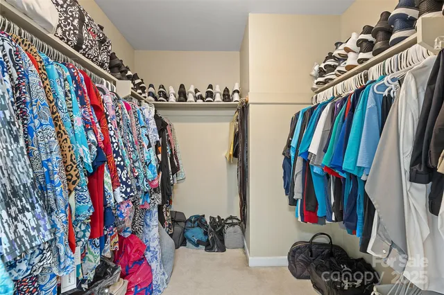 a view of walk in closet with clothes and shoes