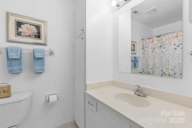 a bathroom with a granite countertop sink a mirror a shower and a toilet