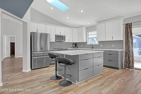 a kitchen with kitchen island granite countertop a sink cabinets and stainless steel appliances