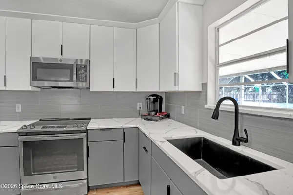 a kitchen with granite countertop white cabinets stainless steel appliances and a window