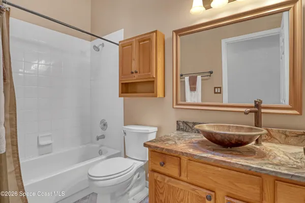 a bathroom with a granite countertop sink a toilet a mirror a bathtub and shower