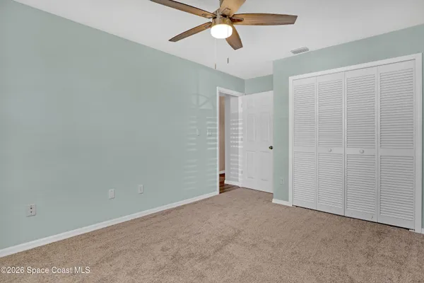 an empty room with closet and a chandelier fan